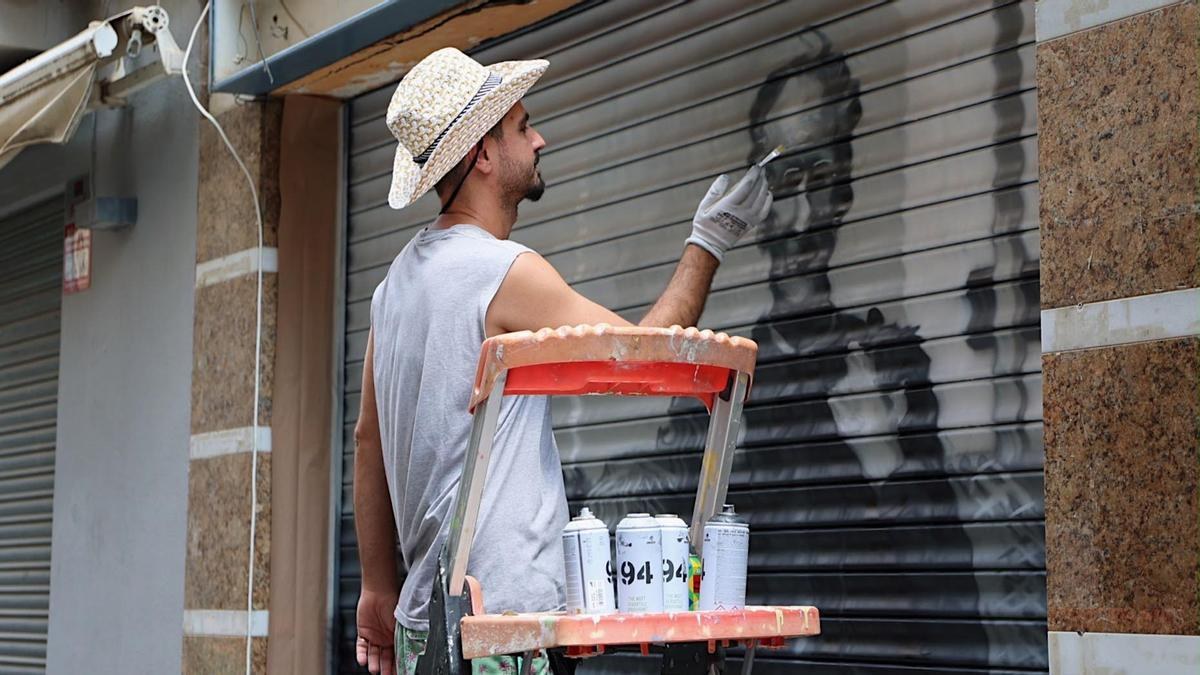 Pau Marinello pintant un mural sobre una persiana amb esprai, Roses